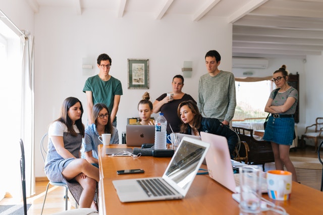 People standing around a laptop working together